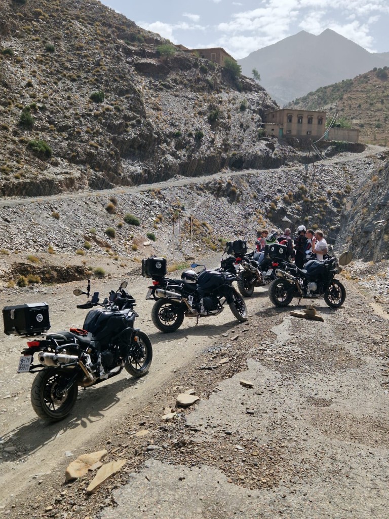 Motos sur piste de montagne — village berbère en arrière-plan